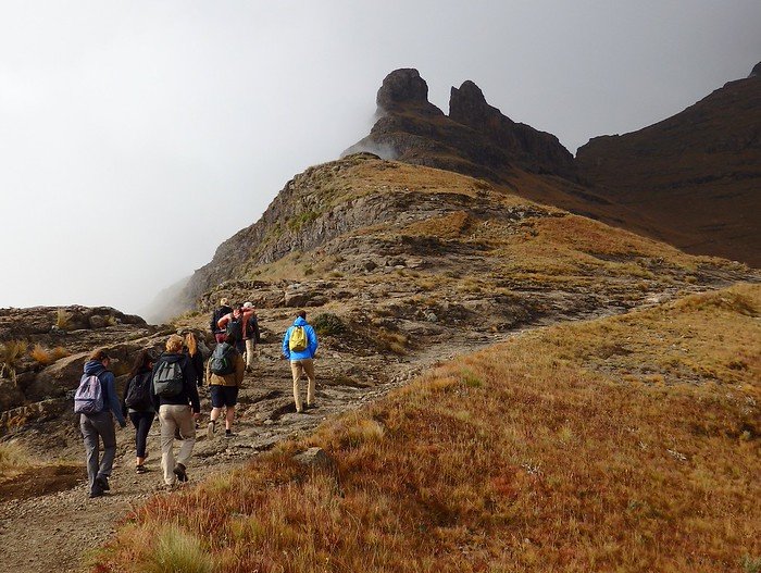 Day hike to Drakensberg, South Africa with a group of hikers making our way up the mountain with backpacks on