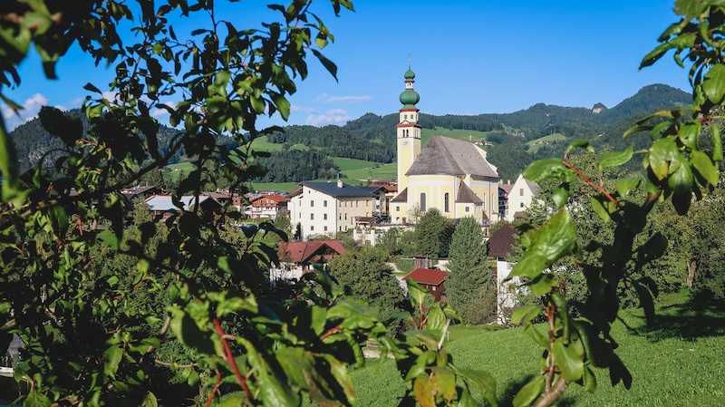 Distinct church in Tirol, Austria as framed by foliage 