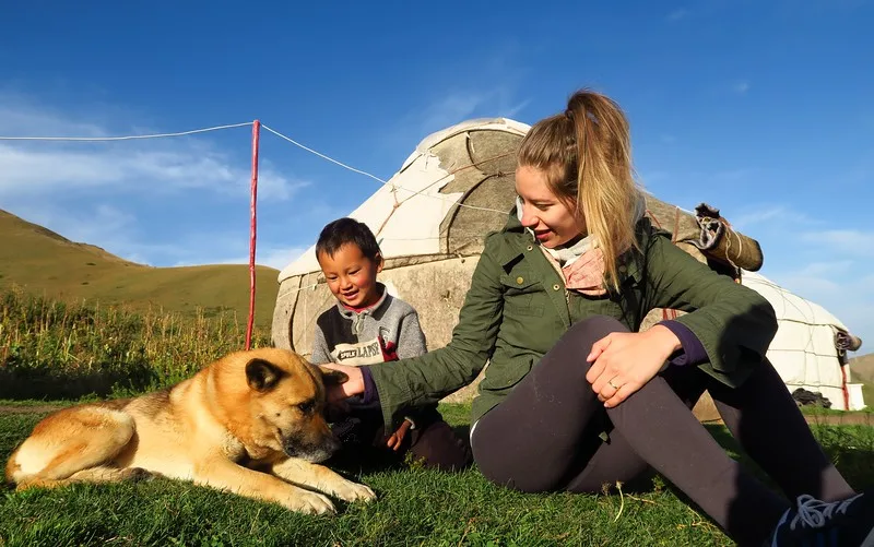 Doing a local yurt stay on our way with Audrey Bergner petting a dog with a cute boy to Song Kol Lake, Kyrgyzstan