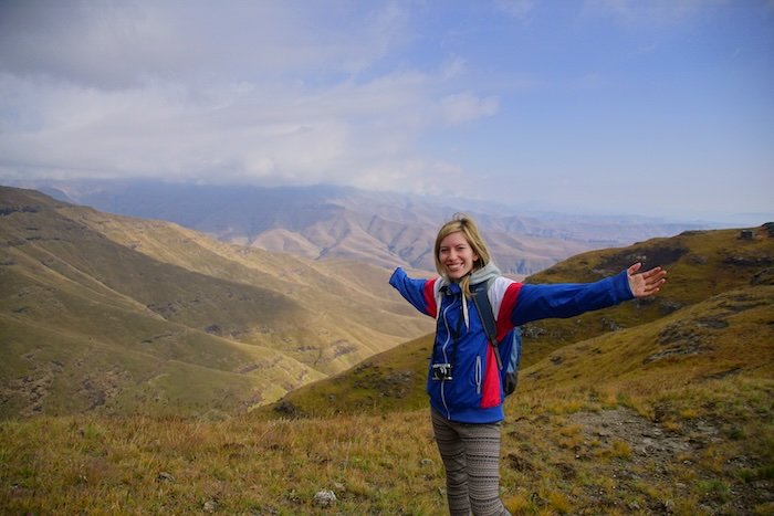 Drakensberg amphitheatre mountain on a hiking trip by That Backpacker Audrey Bergner with arms stretched out admiring the incredible views from a high vantage point 