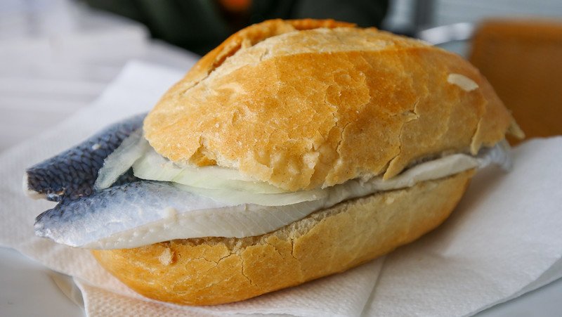 Eating a Bismarck herring sandwich in Hamburg which is a bun filled to the rim with local fish and onions oozing out in Germany Eating a Bismarck herring sandwich in Hamburg which is a bun filled to the rim with local fish and onions oozing out in Germany