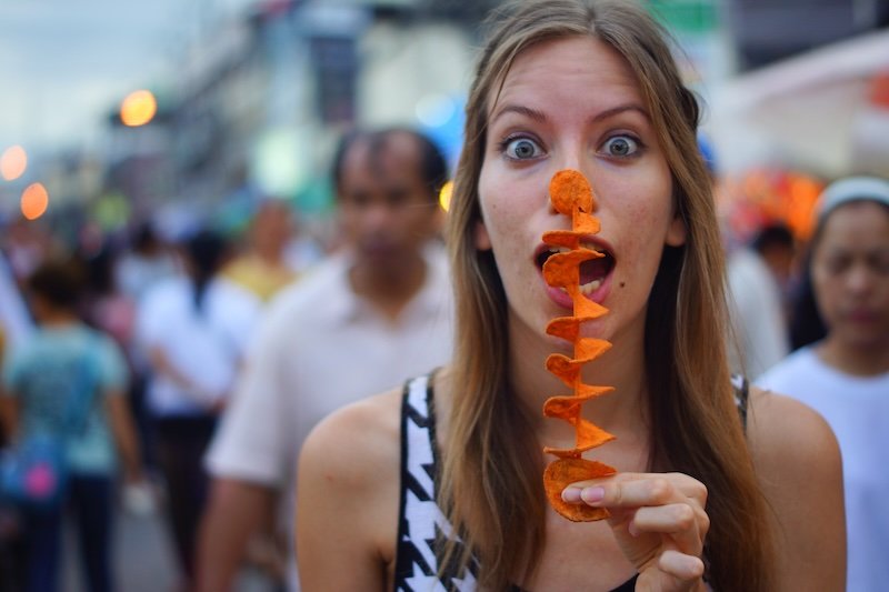 Eating a tornado chip on a skewer at the Chiang Mai night market in Thailand is a hungry That Backpacker Audrey Bergner 