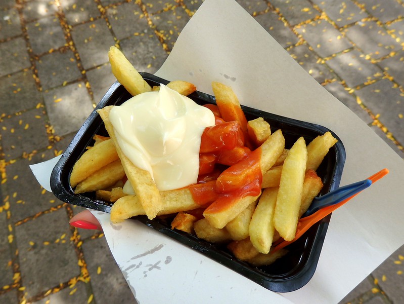 Eating Belgian French Fries loaded up with mayonnaise and ketchup in Bruges, Belgium Eating Belgian French Fries loaded up with mayonnaise and ketchup in Bruges, Belgium
