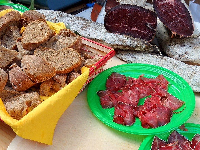 Eating bresaola in Chiavenna, Italy with bread served on plates for locals and tourists to enjoy and savour on the street