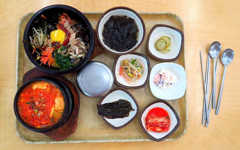 Eating lunch at a jjimjilbang including a diverse spread of food including dolsot bibimbap and banchan in Seoul 