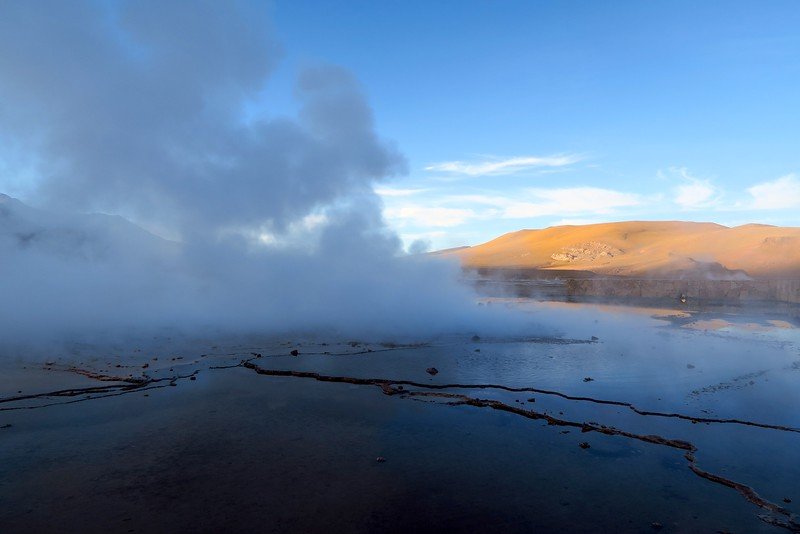 Steam rising from geothermal hot springs at El Tatio Geysers in the Atacama Desert, Chile, during sunrise