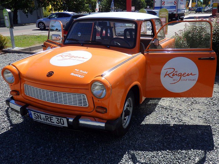 Bright orange Trabant converted to electric power with “Rügen Island – Wir sind Insel” branding, parked outdoors as a fun eco-friendly rental option for exploring Germany’s Baltic Sea island