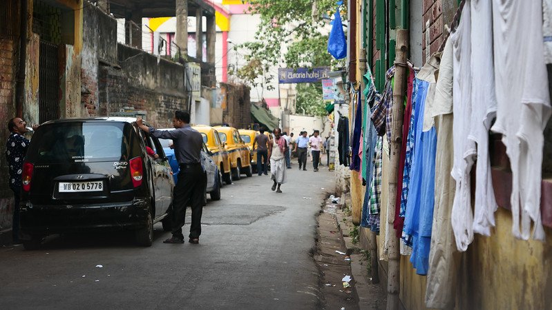 Exploring the streets of Kolkata on foot with clothes hanging on the walls and yellow cabs aplenty in India
