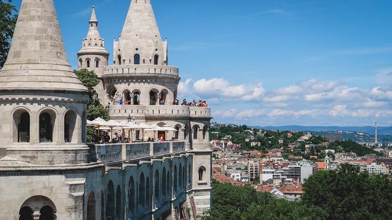 Panoramic view of Budapest from Fisherman’s Bastion, featuring its fairytale-like towers, arched balconies, and sweeping cityscape under a bright blue sky. This popular lookout point offers some of the best views of Budapest, Hungary