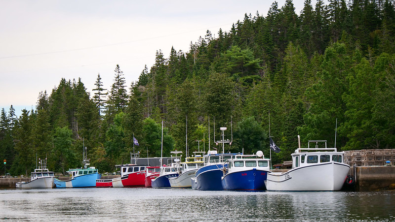 Fishing boats moored at St. Peters Canal on Cape Breton Island with red, blue and white colours on display in Nova Scotia, Canada 