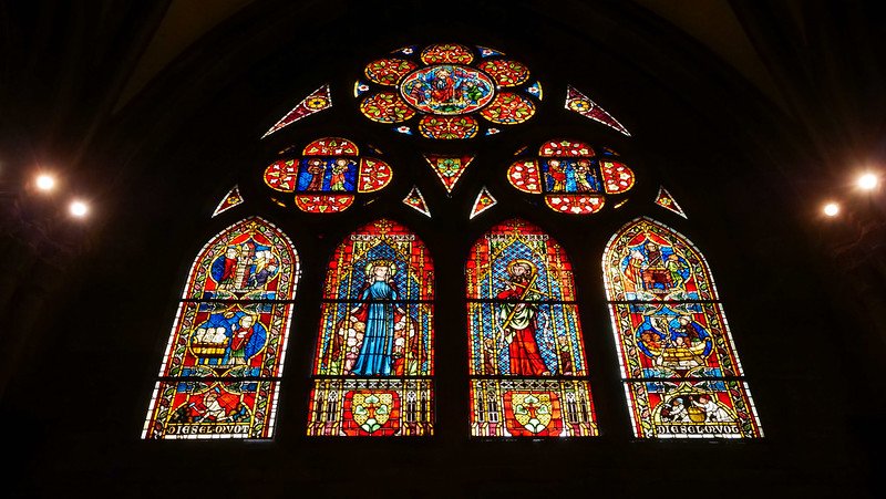 Vibrant medieval stained glass windows inside the Gothic Freiburg Cathedral (Freiburger Münster) in Freiburg im Breisgau, Germany, depicting religious figures and scenes donated by various medieval guilds