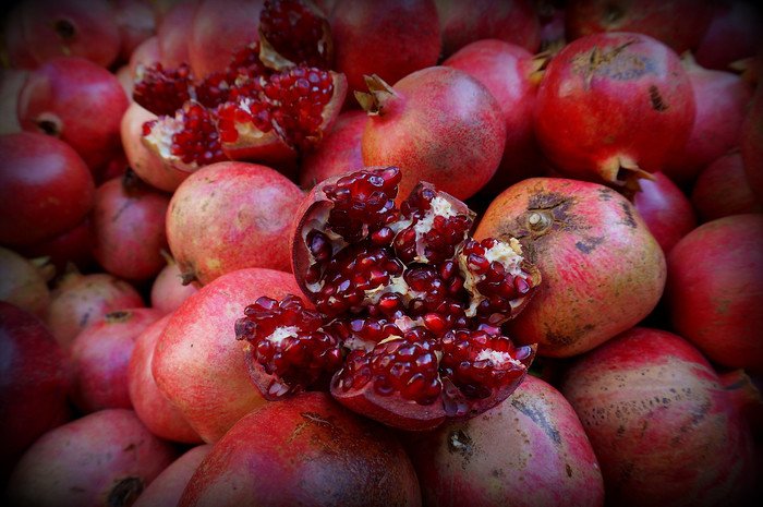 Vibrant pile of ripe pomegranates with one split open to reveal glistening ruby-red seeds at a market stall in Istanbul, Turkey, a popular spot for enjoying freshly squeezed pomegranate juice