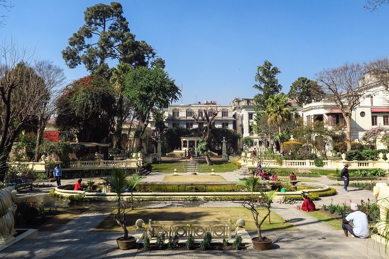 Peaceful Garden of Dreams in Kathmandu, Nepal with neoclassical architecture, manicured lawns, fountains, and visitors relaxing under the warm sun