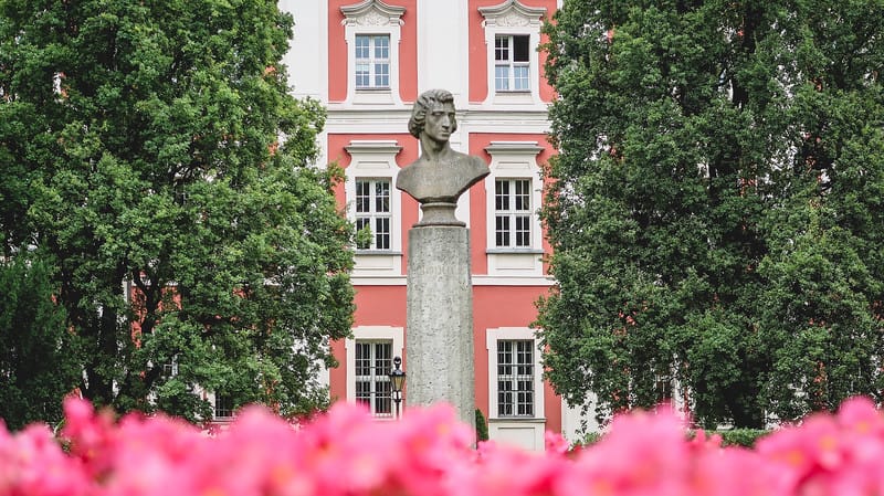 Garden views of the Chopin statue in Poznan with flower foreground and trees and buildings in the background in Poland Garden views of the Chopin statue in Poznan with flower foreground and trees and buildings in the background in Poland