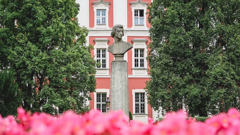 Garden views of the Chopin statue in Poznan with flower foreground and trees and buildings in the background in Poland Garden views of the Chopin statue in Poznan with flower foreground and trees and buildings in the background in Poland