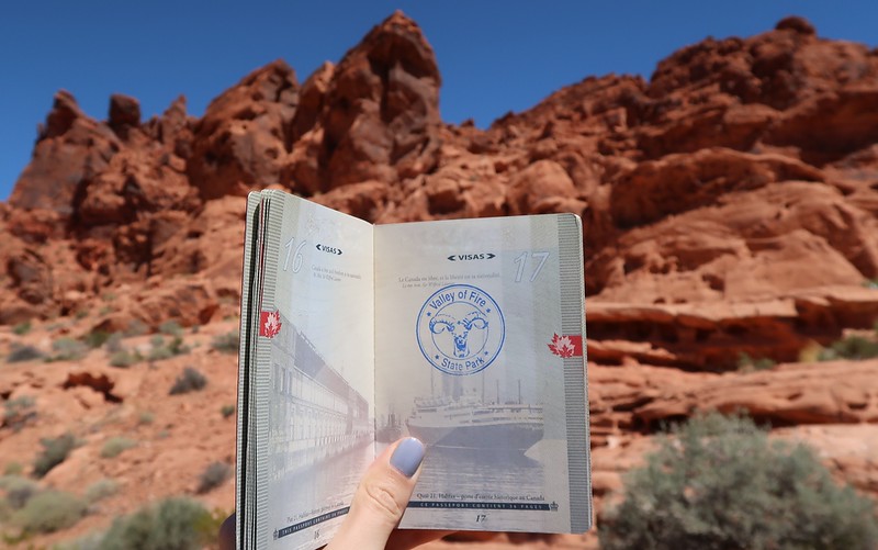 Getting a passport stamp at Valley of Fire holding it up against the naturally stunning landscape backdrop in Nevada 