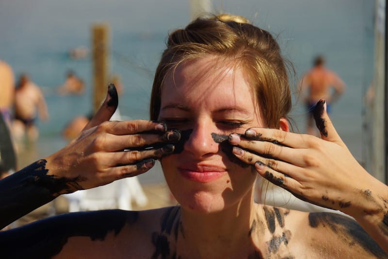 Getting muddy in the Dead Sea covering our faces with it all over with That Backpacker Audrey Bergner face close up views 