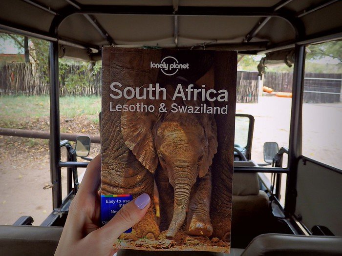 Going on safari in Kruger National Park holding our lonely planet South Africa travel guide book in hand and ready for adventure