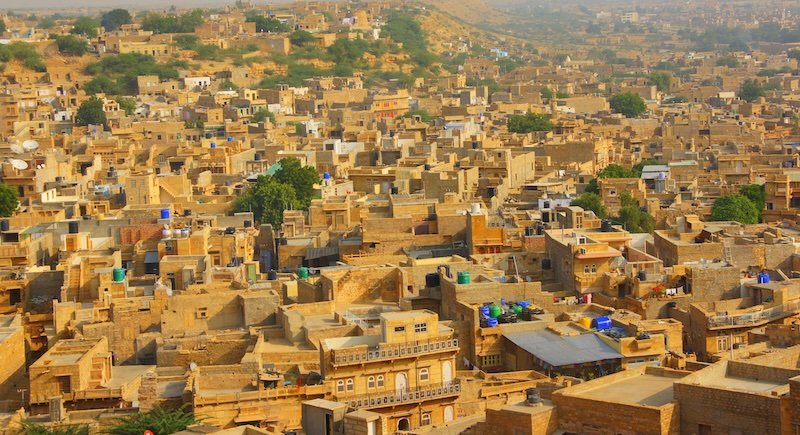 Panoramic view of Jaisalmer in Rajasthan, India showcasing tightly packed golden sandstone houses and havelis glowing in warm desert light