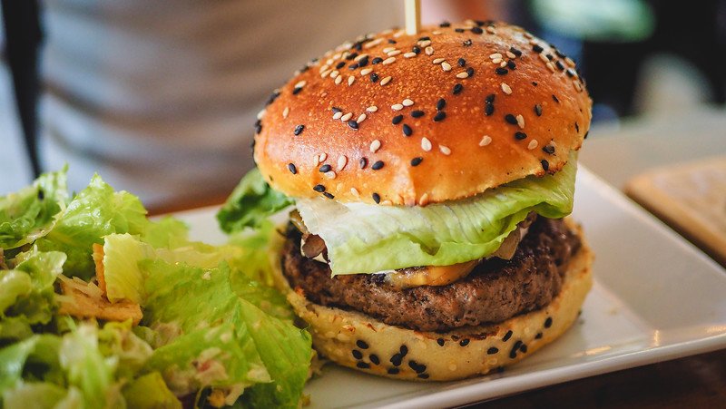 A juicy gourmet burger served on a sesame-seed bun with crisp lettuce and a side green salad at À L’Abordage Microbrasserie in Sutton, Quebec, highlighting the local gastropub’s hearty cuisine