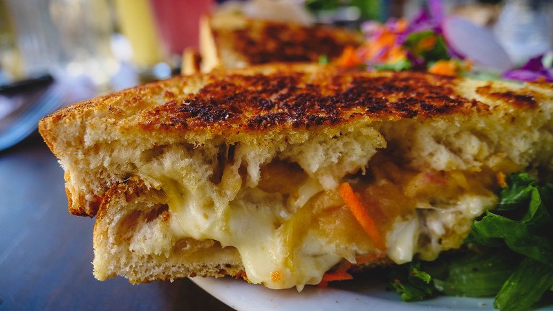 Close-up of a golden grilled cheese and caramelized apple sandwich served with a fresh side salad at Le Cafetier in Sutton, Quebec — a cozy café stop during our Eastern Townships weekend getaway