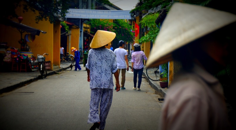 Hoi An ladies with conical hats walking down the street in Vietnam 