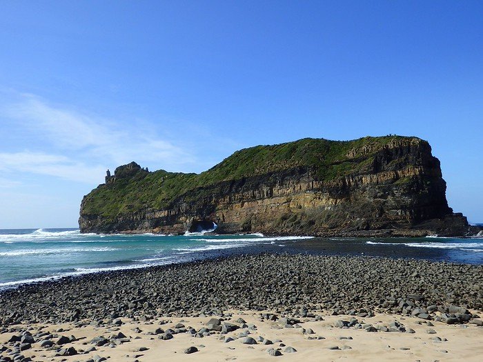 Hole in the Wall located at Coffee Bay in South Africa with rocky beach foreground and distinct geographic features in the background