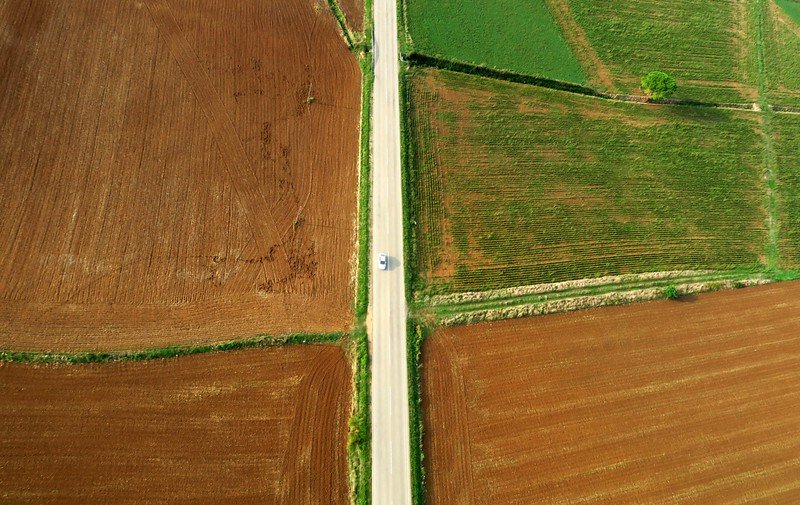 Hot air ballooning in Costa Brava with rural farmland views below and a car driving looking at tiny as an ant below 