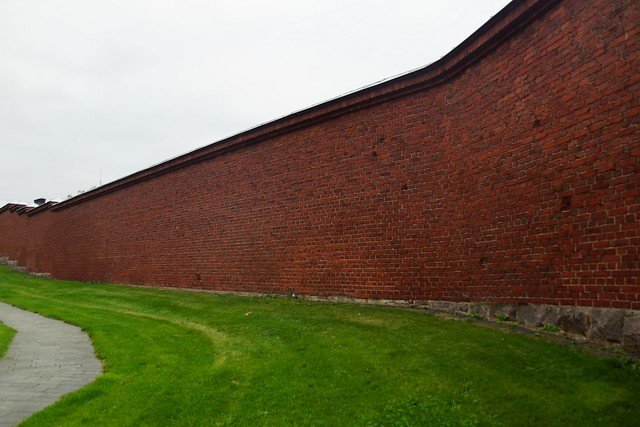 Long red-brick exterior wall of Hotel Katajanokka in Helsinki, Finland, once a prison and now a boutique hotel, symbolizing the transformation of the historic jail into a unique travel destination that blends heritage with modern hospitality