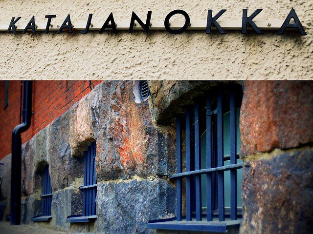 Exterior details of Hotel Katajanokka in Helsinki, Finland, showcasing barred jail windows set in stone walls beneath the hotel’s signage, highlighting the building’s history as a former prison transformed into a unique design and luxury hotel