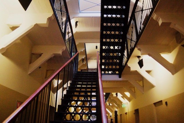 Historic staircase inside Hotel Katajanokka in Helsinki, Finland, showcasing the original iron railings and prison-style architecture transformed into a modern boutique hotel, blending heritage design with contemporary hospitality