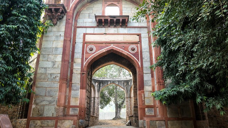 Historic Mughal gateway with arched entrance surrounded by greenery on the grounds of Humayun’s Tomb in Delhi, India