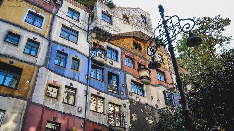 Vibrantly painted façade of the whimsical Hundertwasserhaus in Vienna, Austria, featuring irregular windows, playful balconies, and artistic architectural details surrounded by greenery Vibrantly painted façade of the whimsical Hundertwasserhaus in Vienna, Austria, featuring irregular windows, playful balconies, and artistic architectural details surrounded by greenery