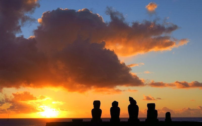 Incredible sunrise with the Moai statues as silhouettes and the clouds on fire 
