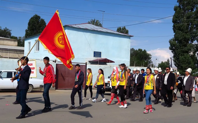 Independence Day Parade in Kochkor, Kyrgyzstan with locals carrying a national flag on the street