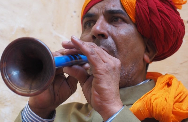 Indian man playing horn at the fort in Jodhpur, India 