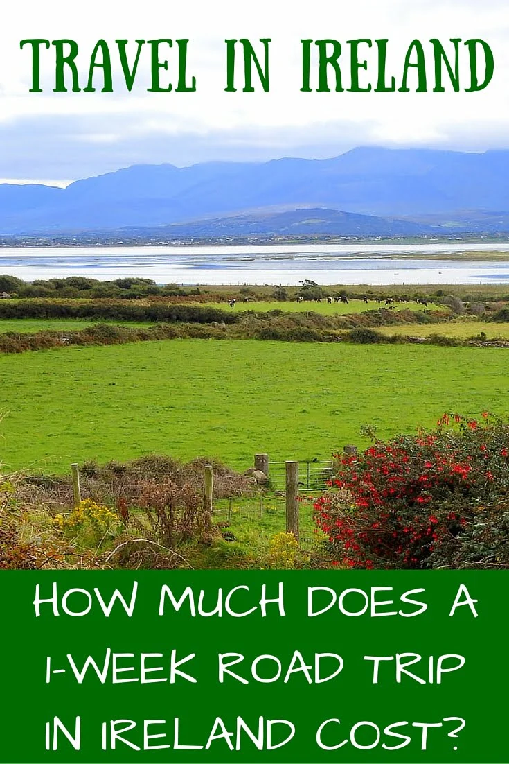 Pinterest cover graphic for a Ireland road trip travel budget guide, featuring a scenic view of lush green fields, hedgerows, and a calm bay with blue mountains in the background under cloudy skies, overlaid with text reading “Travel in Ireland: How much does a 1-week road trip in Ireland cost?”