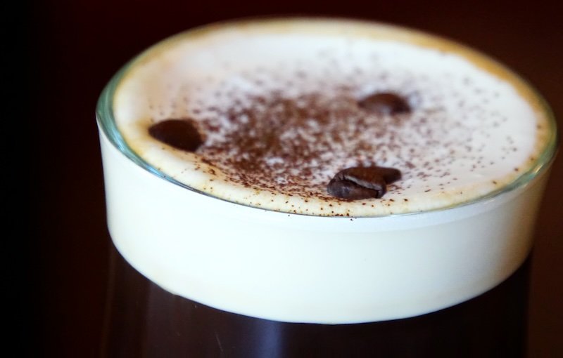 Irish Coffee in Dublin topped with thick cream, cocoa powder, and coffee beans on a glass of hot whiskey coffee