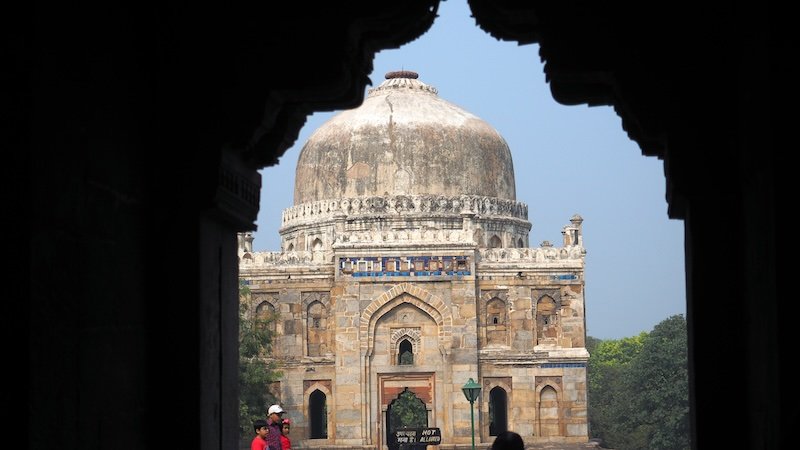 Framed view of Isa Khan’s Tomb in Delhi through an arched doorway, showcasing Indo-Islamic Mughal architecture and intricate stonework