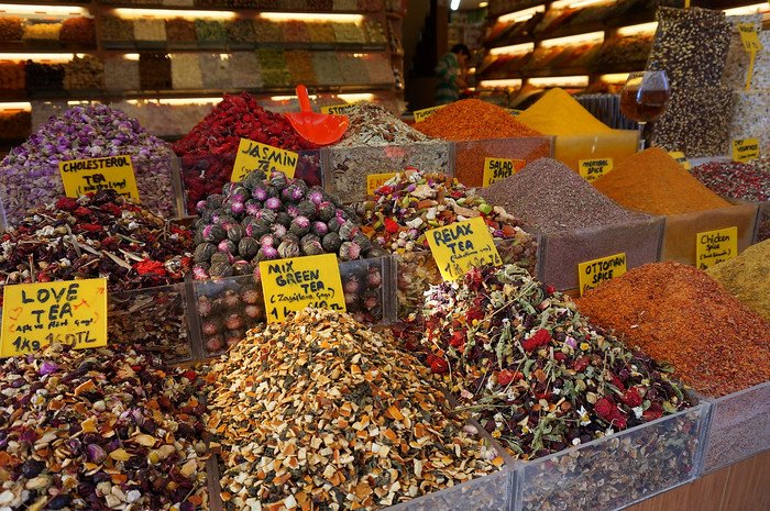 Colorful mounds of loose leaf teas and spices on display at the Spice Bazaar in Istanbul, Turkey, including blends like jasmine, love tea, relax tea, and Ottoman spice