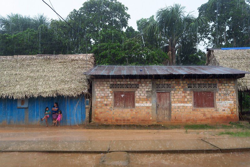 It rains a lot in the Amazon with locals taking cover at the village under the thatched roof as it is pouring like crazy outside!