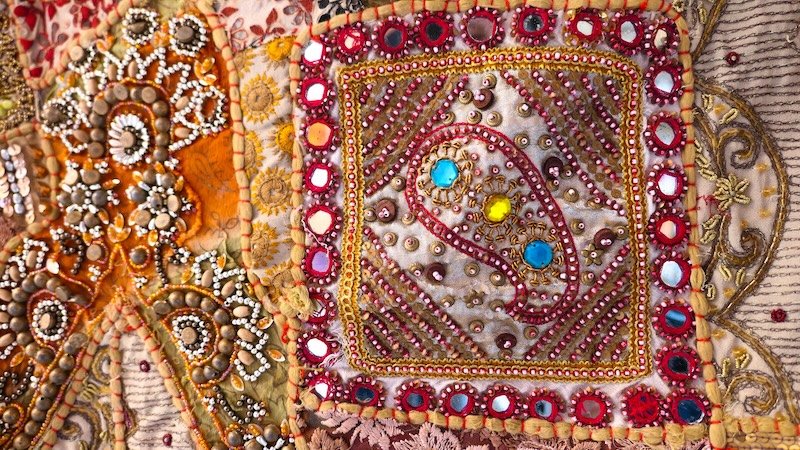 Close-up of an ornate hand-embroidered textile in Jaisalmer, India, showcasing intricate beadwork, sequins, and vibrant thread patterns typical of Rajasthan’s traditional craftsmanship