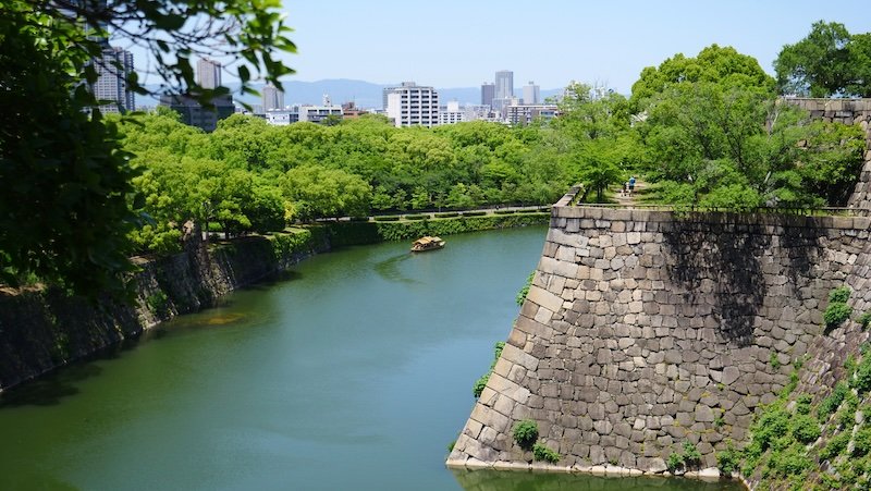 Japanese boat like a tiny spec off in the distance touring around Osaka Castle moat in Japan 