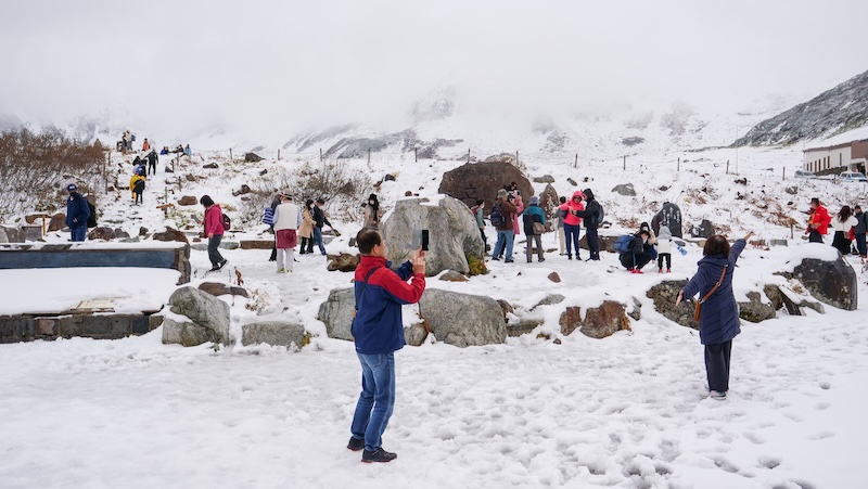 Japanese tourists taking photos in the snow during the Tateyama Kurobe Alpine crossing over the roof of Japan 