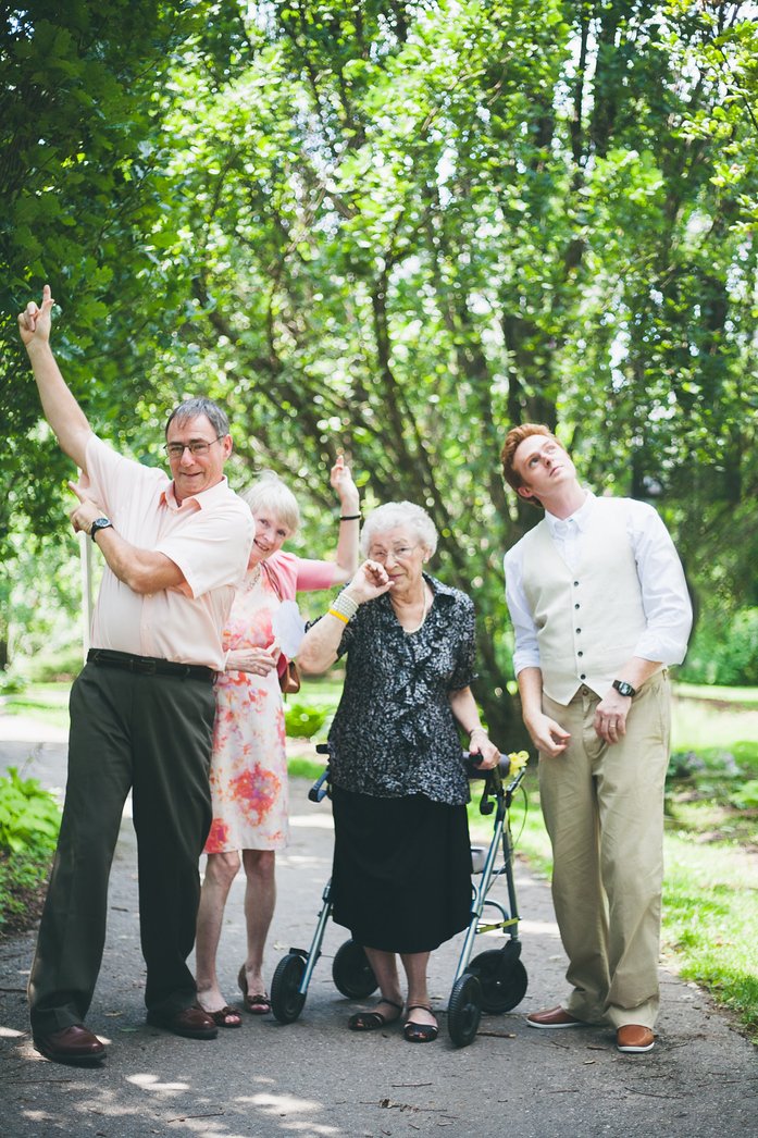 Playful Jeffery family portrait at Samuel and Audrey’s summer wedding in Brampton, Ontario, with relatives striking fun poses under lush green trees, including grandmother with walker, capturing candid joy and family togetherness on the big day