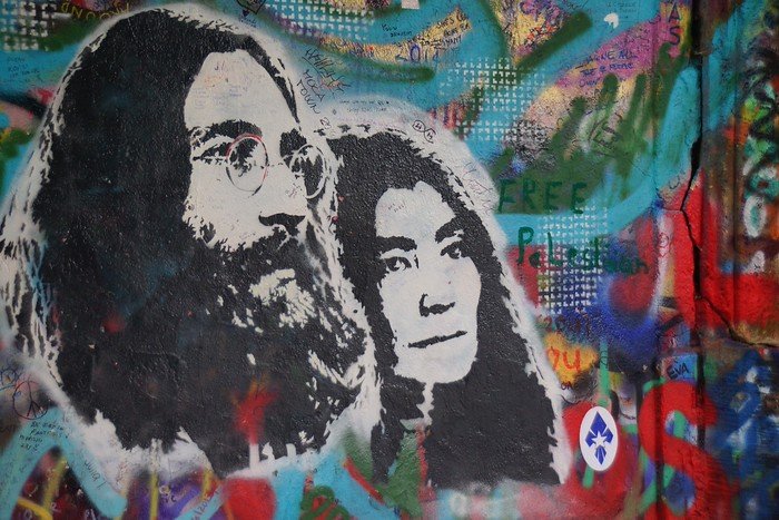 Colorful street art mural of John Lennon and Yoko Ono painted on the vibrant Lennon Wall in Prague, Czech Republic, covered in layers of peace messages and graffiti