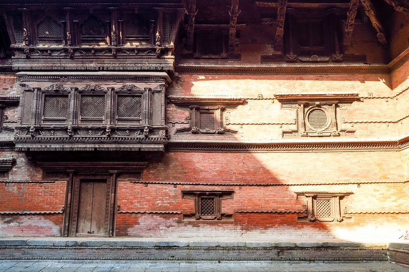 Close-up of intricate Newar wood carvings on a traditional red-brick temple in Kathmandu Durbar Square, Nepal, showcasing historic architecture and cultural craftsmanship