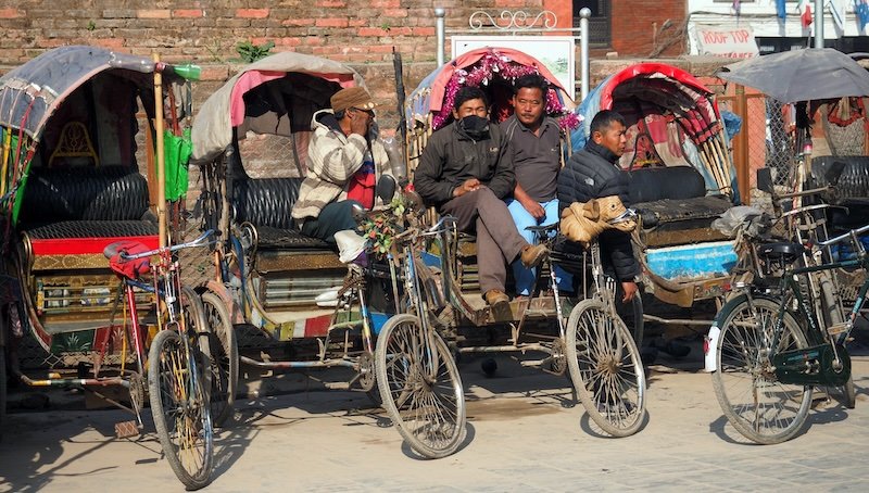 Cycle rickshaw drivers waiting for passengers in Kathmandu, Nepal, showcasing traditional transportation still used in the bustling city