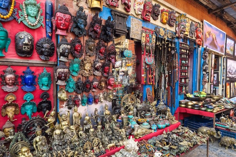 Colorful souvenir shop in Kathmandu, Nepal, selling traditional masks, Buddha statues, jewelry, and handmade crafts in the city’s bustling markets