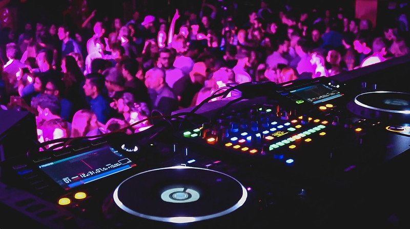 DJ booth with colorful turntables and sound equipment overlooking a lively dance floor at KOKO London in Camden, where a packed crowd enjoys live music, nightlife energy, and vibrant club culture inside one of the city’s most iconic venues